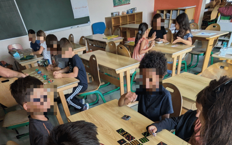 Enfants autour d'un jeu de société lors d'une classe apprenante animée par À VAUX JEUX