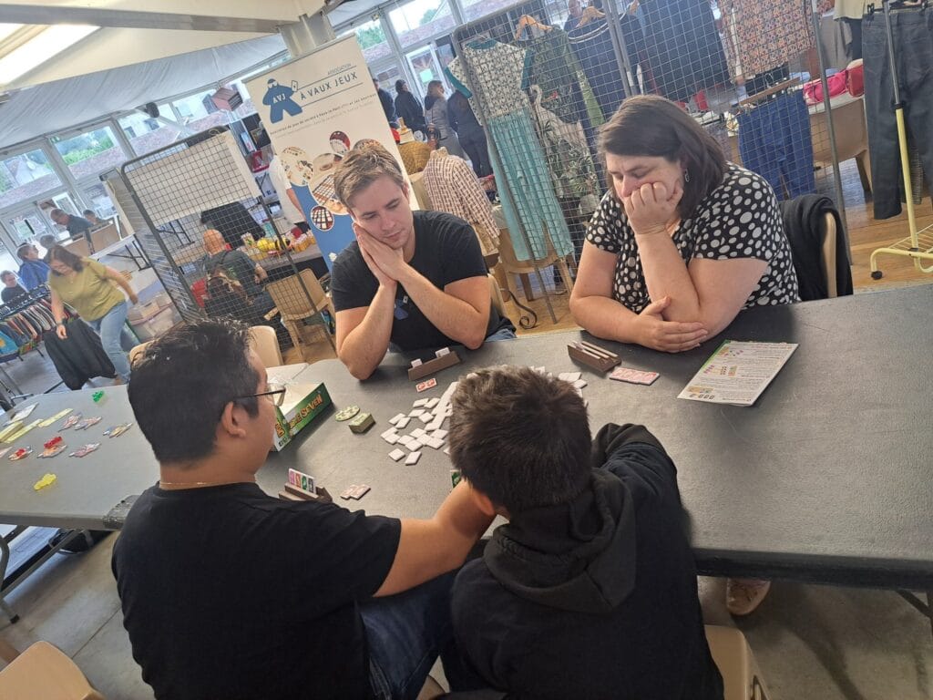 Adhérents concentrés autour d'une partie de jeu de société lors d'une animation À VAUX JEUX