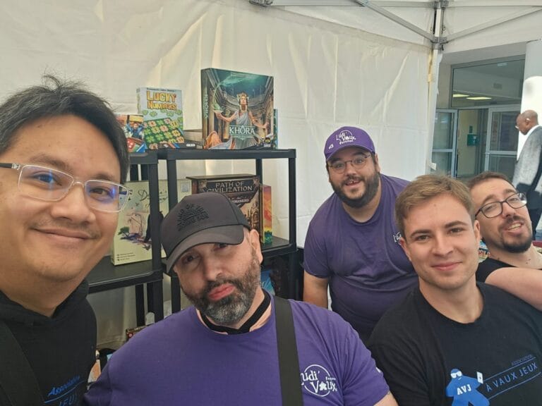 Bénévoles d'À VAUX JEUX souriants sur le stand de l'association au Forum des associations de Vaux-le-Pénil, devant une étagère de jeux de société
